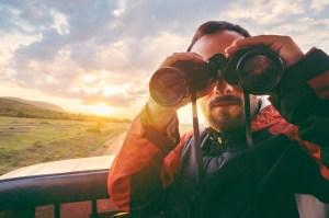 Man with binoculars at sunset